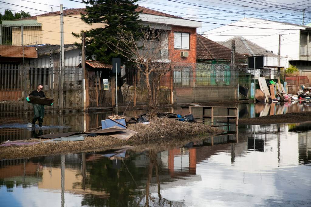 rua alagada, com acúmulo de entulhos em frente às casas